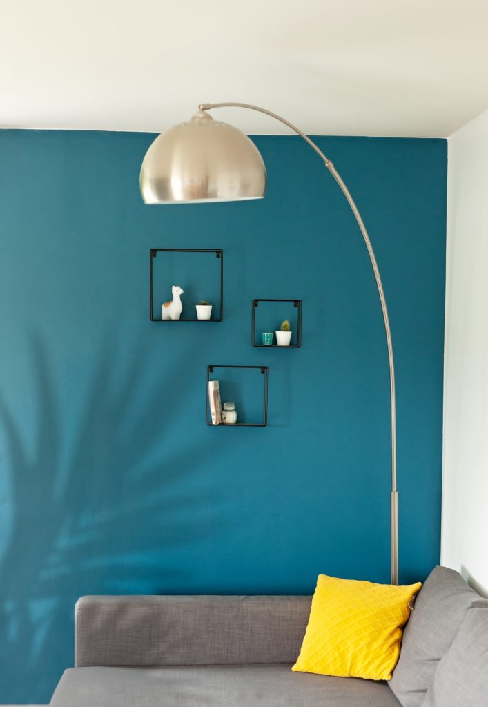 Modern apartment, blue wall, grey sofa with yellow pillow
